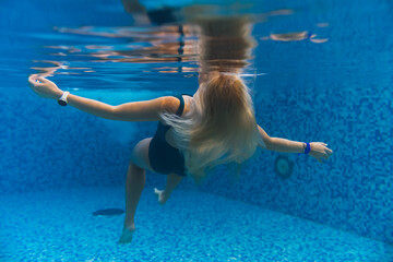 Underwater photo, blonde girl drowning in the pool.
