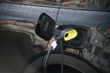 Closeup of black electric car charging at the station in the street - 768012698
