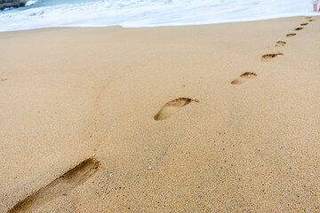 footprints in the sand with a wave as background