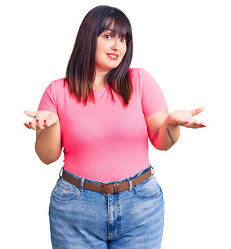 Young plus size woman wearing casual clothes clueless and confused expression with arms and hands raised. doubt concept.