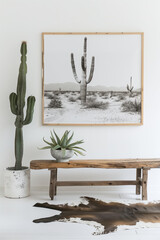 A white wall with a wood frame and cactus print, rustic wooden bench in front of it, white floor with cowhide rug, black and white photo of desert landscape, green plants on the side - obrazy, fototapety, plakaty