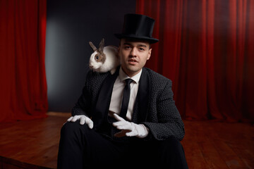 Showman in suit sitting on theatre stage resting after magic show