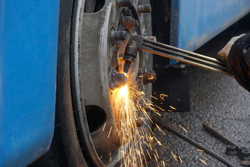 A welder cuts a damaged nut from a bus wheel using an autogen.