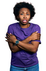 African american woman with afro hair wearing casual purple t shirt shaking and freezing for winter...