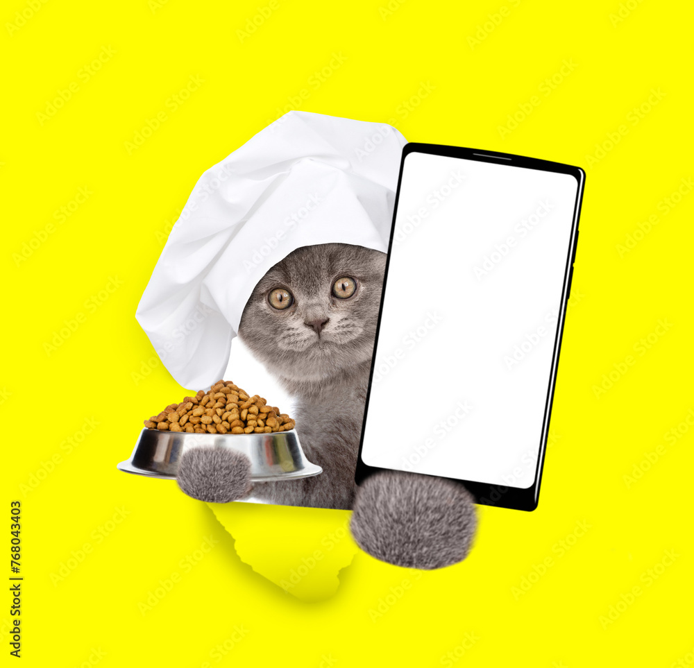 Aufkleber cute cat wearing chef's hat looks through a hole in yellow paper, holds empty bowl and shows smartph