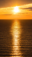 Beautiful golden sunset on the sea. Sunset over the water in the Black Sea. Reflection of sunset sunlight on the surface of the water. Vertical photo.