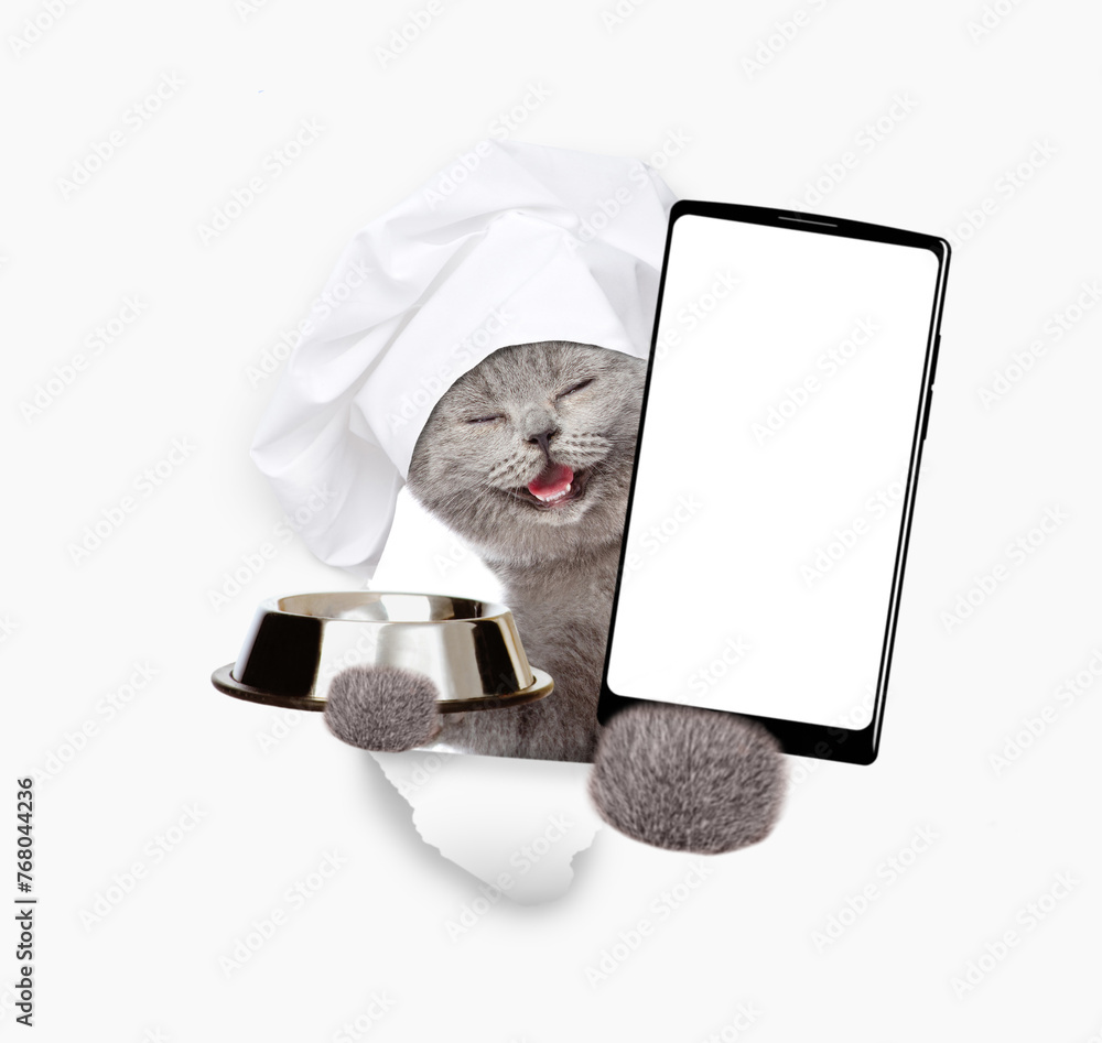 Aufkleber happy cat wearing chef's hat looks through a hole in white paper, holds empty bowl and shows smartph