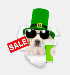 Saint Patrick's Day concept. Cute Golden retriever puppy wearing green hat of the leprechaun looks...