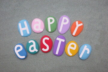 Happy Easter, creative celebration with hand painted multi colored stone letters over green sand