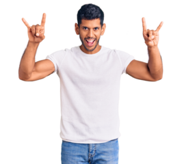 Young latin man wearing casual clothes shouting with crazy expression doing rock symbol with hands up. music star. heavy music concept.