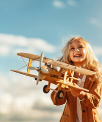 Cute little girl playing with a toy airplane on the blue sky background