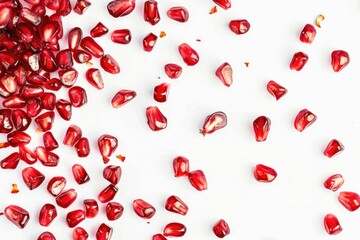 scattered pomegranate seeds against a white background