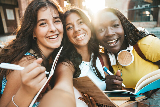 Happy female teenagers taking selfie outdoors - University students in college campus smiling together at camera - Technology and educational concept