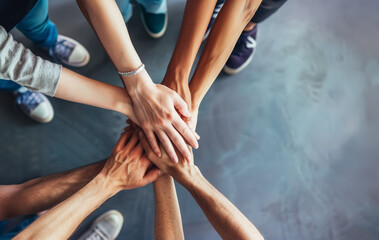 Top view of diverse hands united over a concrete background, symbolizing teamwork and unity.