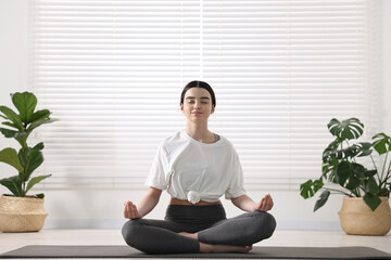 Beautiful girl meditating on mat in yoga studio