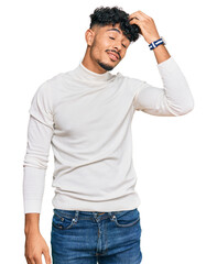 Young arab man wearing casual winter sweater smiling confident touching hair with hand up gesture, posing attractive and fashionable