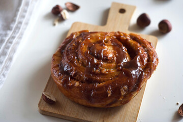 A bun with caramel and nuts lies on a board on the table