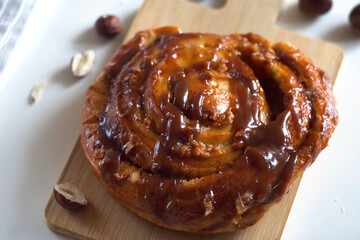 A bun with caramel and nuts lies on a board on the table
