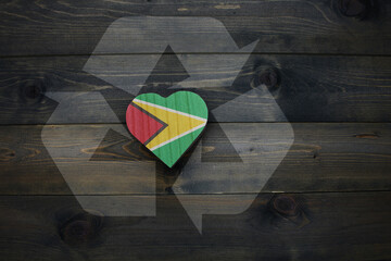 wooden heart with national flag of guyana near reduce, reuse and recycle sing on the wooden...