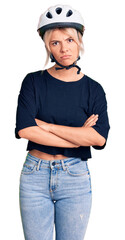 Young beautiful blonde woman wearing bike helmet skeptic and nervous, disapproving expression on face with crossed arms. negative person.