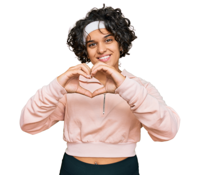 Young hispanic woman with curly hair wearing sportswear smiling in love showing heart symbol and shape with hands. romantic concept.