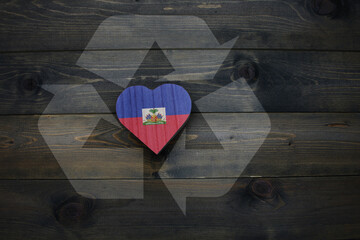 wooden heart with national flag of haiti near reduce, reuse and recycle sing on the wooden background.concept