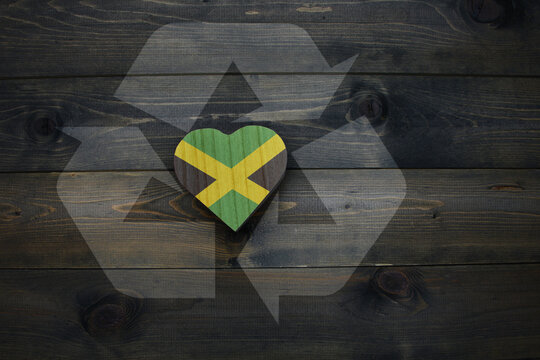 wooden heart with national flag of jamaica near reduce, reuse and recycle sing on the wooden background.concept