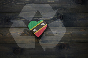 wooden heart with national flag of saint kitts and nevis near reduce, reuse and recycle sing on the wooden background.concept
