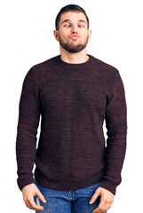 Young handsome man wearing casual sweater making fish face with lips, crazy and comical gesture. funny expression.