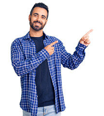 Young hispanic man wearing casual clothes smiling and looking at the camera pointing with two hands...