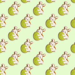 Bunny-shaped cookies with an Easter egg. Festive Easter pattern on light green background. Top view.
