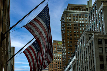 American flags flying on the skyscrapers in the middle of Manhattan, in the streets of the Big...