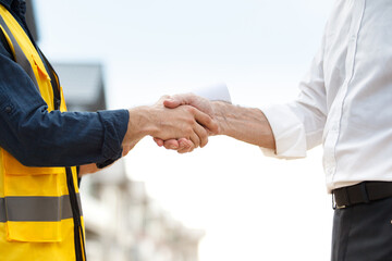 Unrecognizable foreman and businessman shaking hands together at the construction site after...