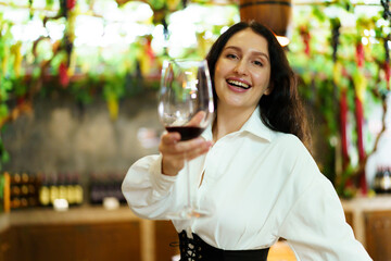 Portrait of beautiful caucasian young woman enjoy testing the red wine and showing a wine glass to camera. 