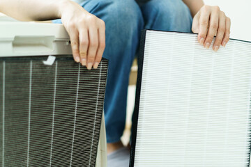 Woman replaces a dirty and dusty air purifier filter in living room. 