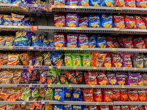 large variety of  potato and corn chips on a store shelf 