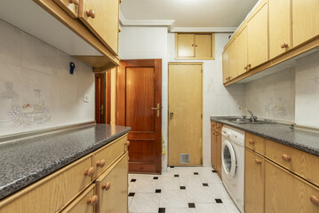 A kitchen with old light wood furniture, a pantry with matching door and integrated white appliances