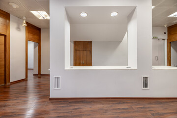 An empty office with smooth white painted walls, a white countertop between pillars, built-in...