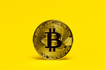 physical coin of the bitcoin cryptocurrency in the center of the image on a yellow background, concept of web3 and blockchain technology