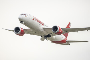 A passenger plane has just taken off from an airport and is folding the landing gear into its...