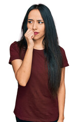 Young hispanic girl wearing casual t shirt looking stressed and nervous with hands on mouth biting nails. anxiety problem.