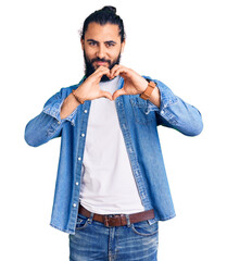Young arab man wearing casual denim shirt smiling in love showing heart symbol and shape with...