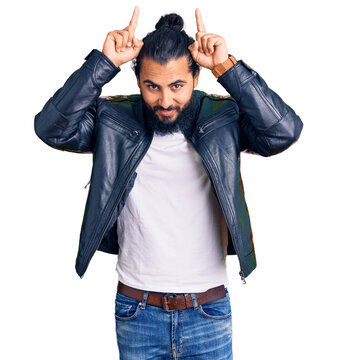 Young arab man wearing casual leather jacket doing funny gesture with finger over head as bull horns