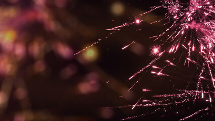 pink fireworks at the edge of abstract blurred lighted sky background with copy space, festive...