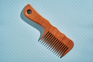 Wooden comb on a pink polka dot background.
