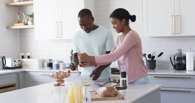 A diverse couple is preparing breakfast together in a modern kitchen