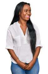 Young black woman wearing casual clothes looking away to side with smile on face, natural expression. laughing confident.