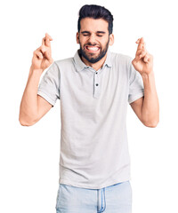 Young handsome man with beard wearing casual polo gesturing finger crossed smiling with hope and eyes closed. luck and superstitious concept.
