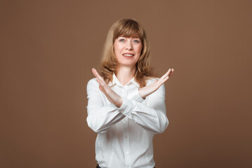 Self-assured Middle-Aged Woman in Her Prime Assertively Gesturing with Hands in a Stop Sign. Concept of a Confidence, Assertiveness, and Setting Boundaries