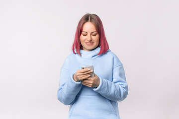 Portrait of smiling young woman holding and texting on mobile phone, checking social networks....